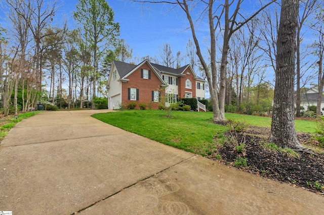 view of front of house featuring driveway, brick siding, a garage, and a front yard