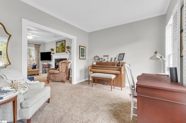 sitting room with carpet flooring, baseboards, a fireplace, ornamental molding, and ceiling fan