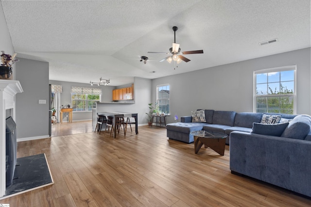 29 Parkgate Ct, Simpsonville, SC 29680 - living area featuring a ceiling fan, light wood-style flooring, lofted ceiling, a textured ceiling, and a fireplace with flush hearth