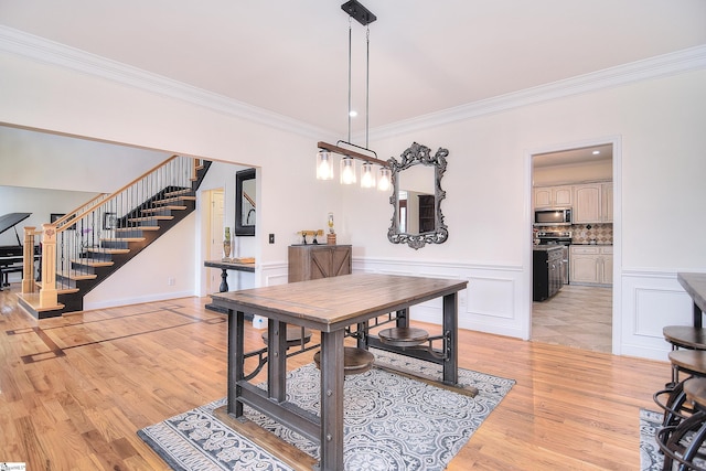 dining space featuring ornamental molding, a decorative wall, stairway, and light wood finished floors