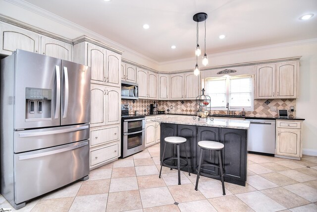 kitchen featuring cream cabinets, appliances with stainless steel finishes, and a breakfast bar