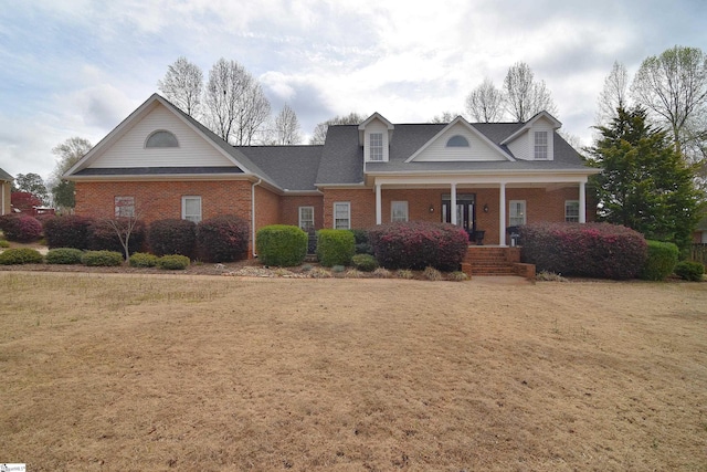 neoclassical home with a porch, brick siding, and roof with shingles