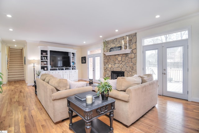 living room with a healthy amount of sunlight, ornamental molding, french doors, and stairway