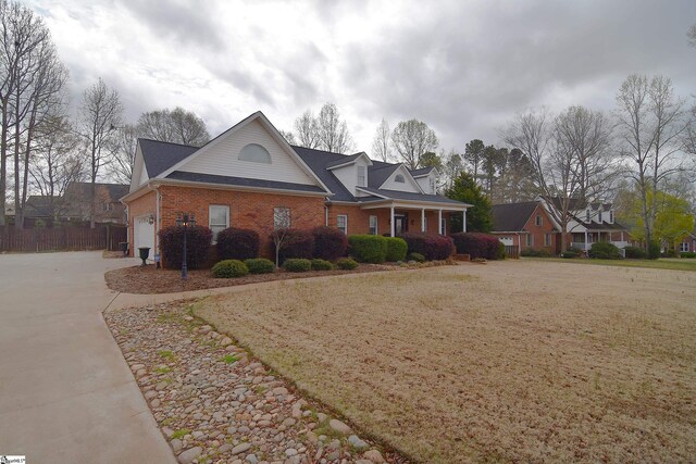 view of front of home featuring fence, a garage, brick siding, and concrete driveway