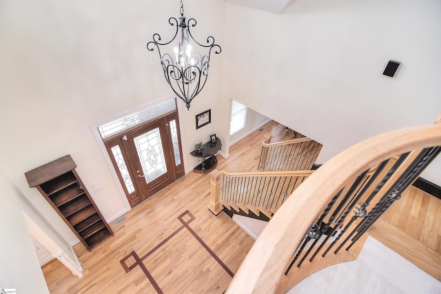 foyer with visible vents, a high ceiling, wood finished floors, and a chandelier
