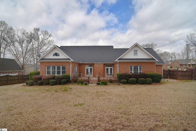 view of front facade featuring brick siding, a front lawn, fence, and a wooden deck