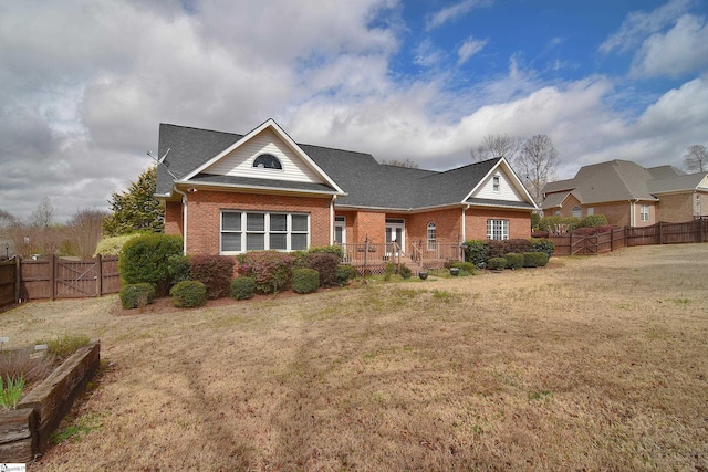 view of front of property featuring a fenced backyard, brick siding, a shingled roof, and a front lawn