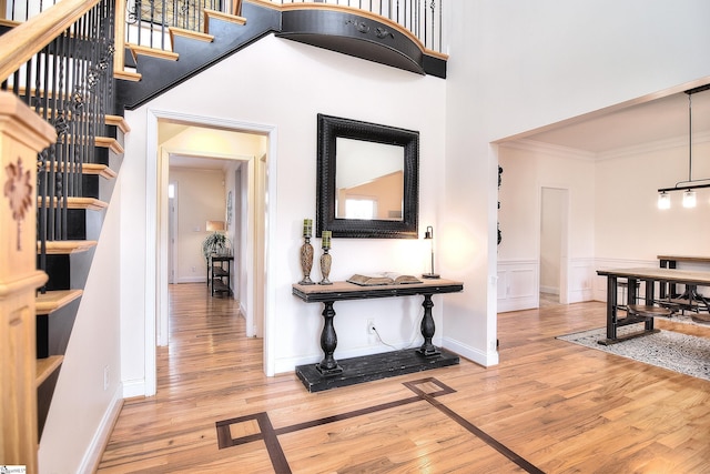 corridor featuring a towering ceiling, ornamental molding, stairs, and wood finished floors