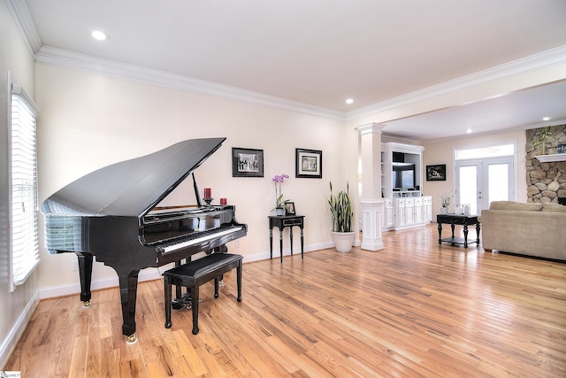 living area featuring light wood finished floors, crown molding, french doors, and ornate columns