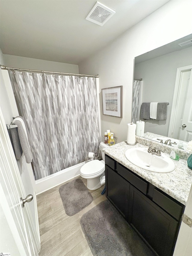 full bathroom with toilet, visible vents, wood finished floors, and vanity