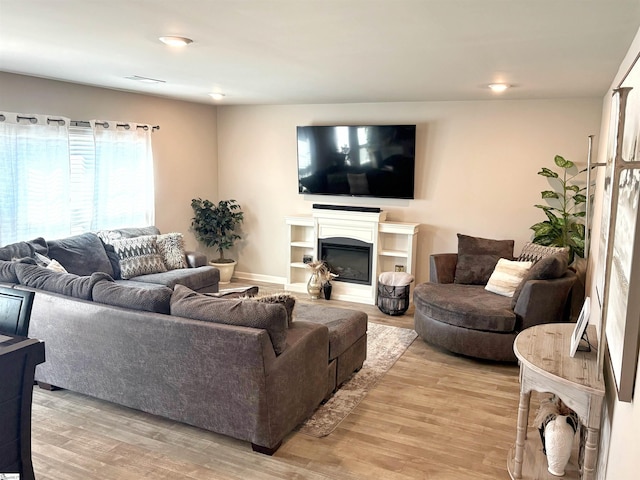 living room with light wood-style floors and a glass covered fireplace