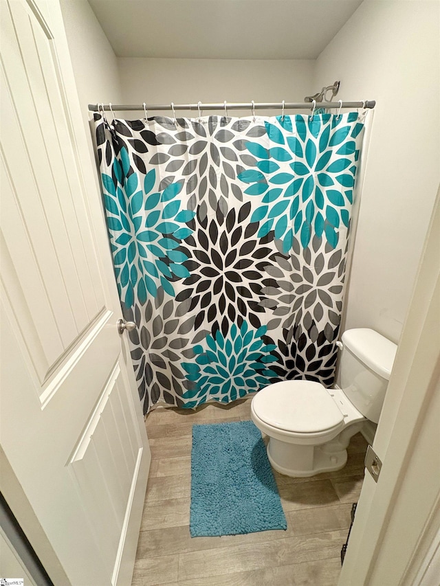 full bath with wood finished floors, toilet, and curtained shower