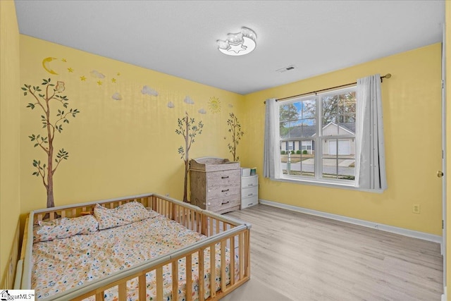 22 Kavanagh Ct, Greenville, SC 29611 - bedroom featuring visible vents, baseboards, wood finished floors, and a nursery area
