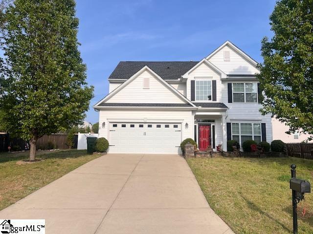 traditional home featuring an attached garage, a front lawn, fence, and concrete driveway