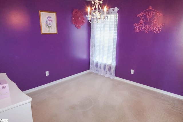 carpeted spare room with baseboards and a chandelier