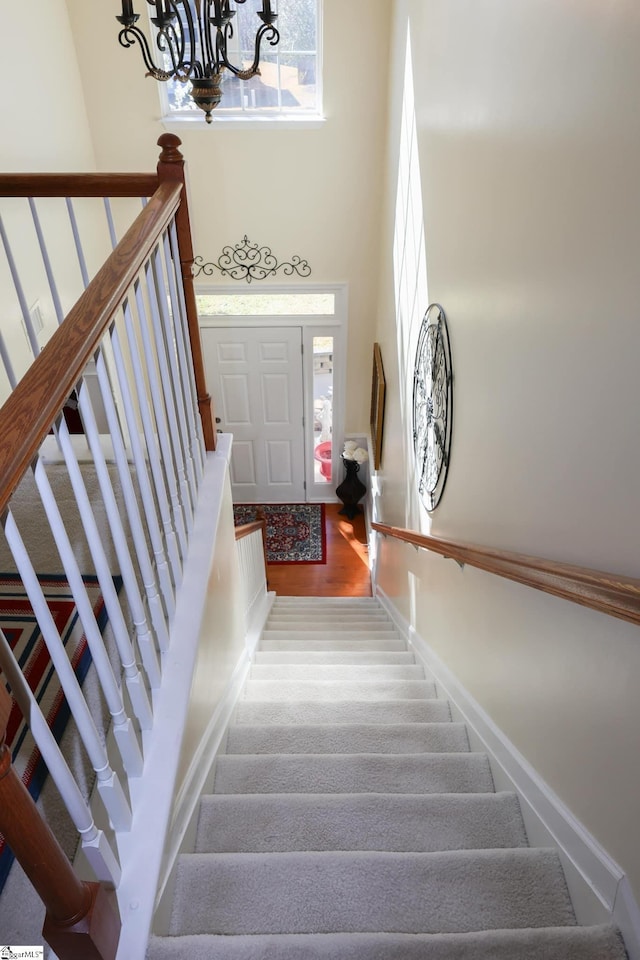 staircase with baseboards, an inviting chandelier, and a wealth of natural light