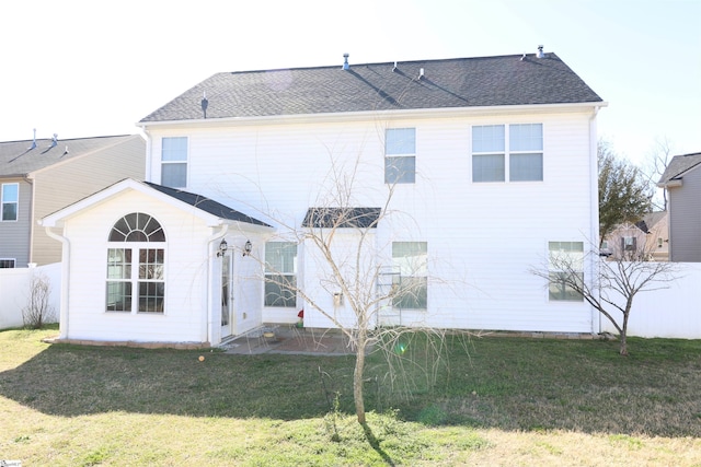 rear view of house featuring a lawn, fence, and roof with shingles