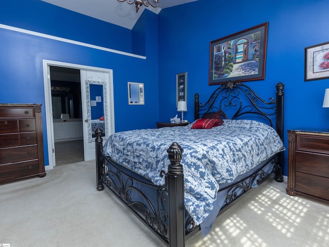 carpeted bedroom featuring a notable chandelier and ensuite bath