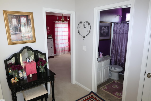 hall featuring baseboards, a notable chandelier, and carpet