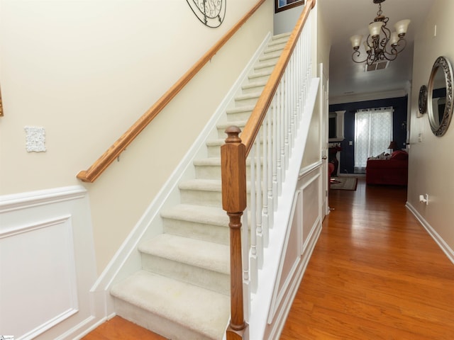 stairs with a chandelier and wood finished floors