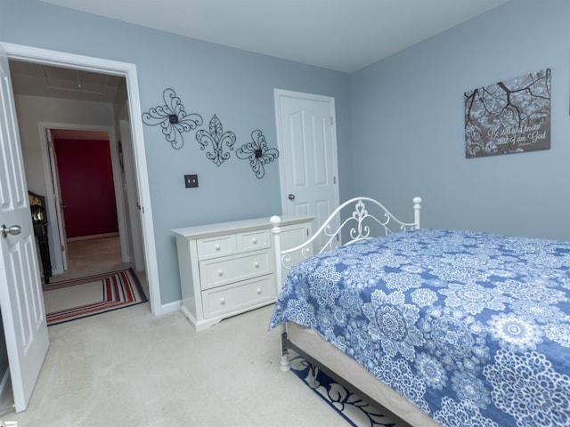bedroom with light colored carpet, attic access, and baseboards