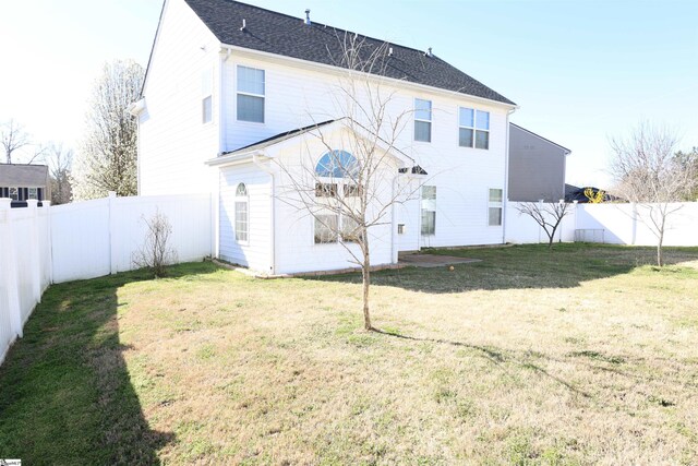 rear view of property featuring a fenced backyard and a lawn
