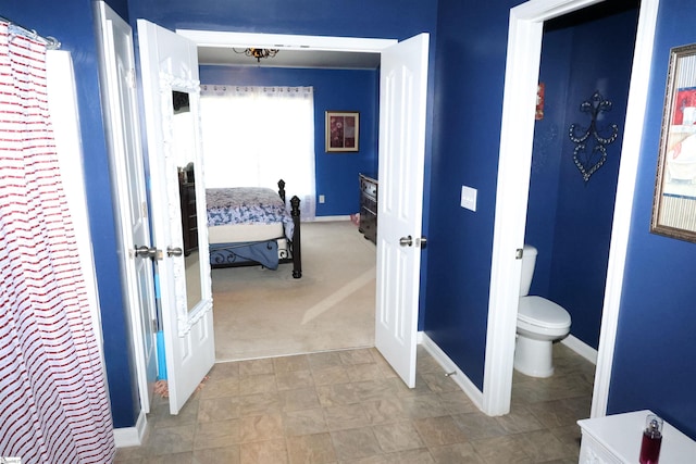 ensuite bathroom featuring toilet, baseboards, and ensuite bath