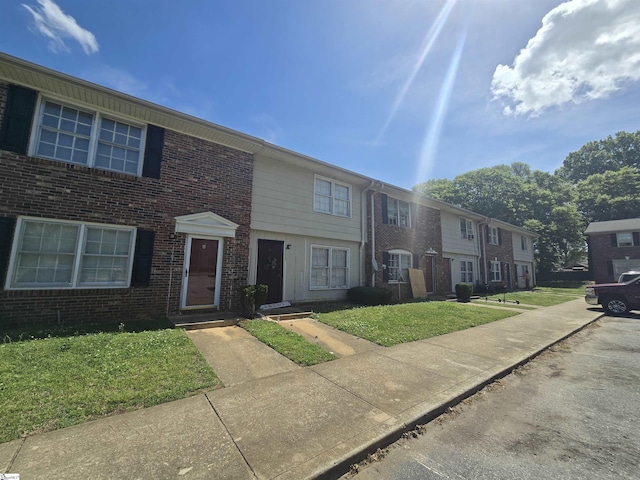 view of property with a front lawn and brick siding