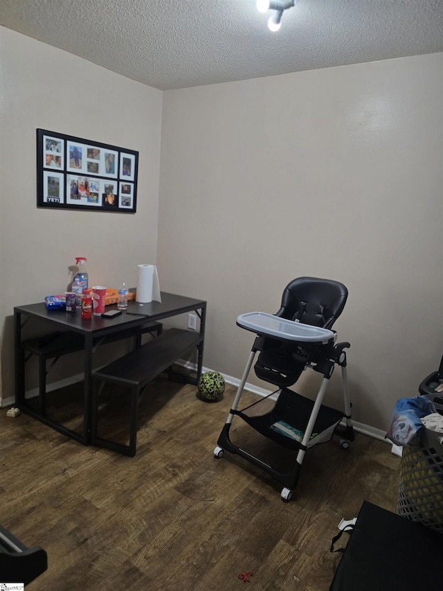 workout room featuring a textured ceiling, baseboards, and wood finished floors