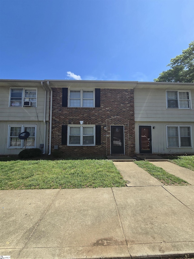 multi unit property with a front yard and brick siding