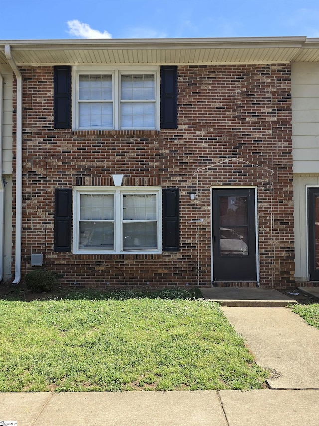 multi unit property featuring a front lawn and brick siding