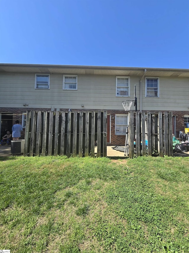 back of house with a lawn, brick siding, and fence