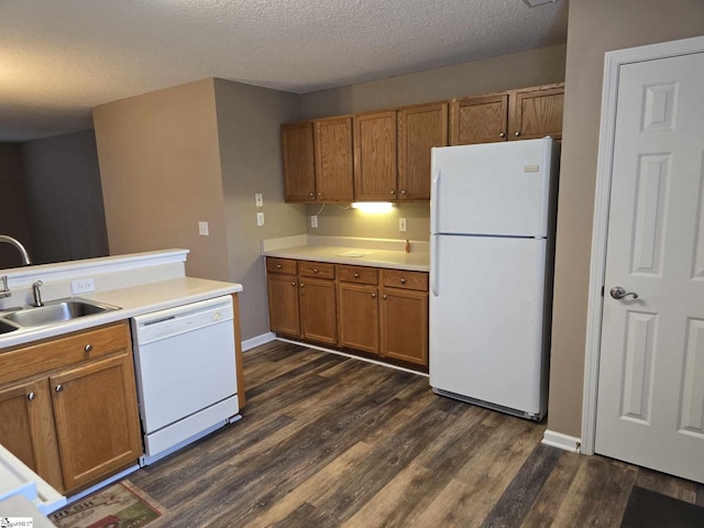kitchen featuring light countertops, white appliances, brown cabinets, a sink, and dark wood-style floors