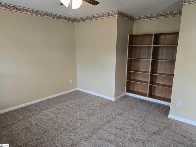 carpeted spare room featuring baseboards, a textured ceiling, and ceiling fan