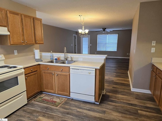 kitchen featuring white appliances, under cabinet range hood, a sink, a peninsula, and brown cabinetry