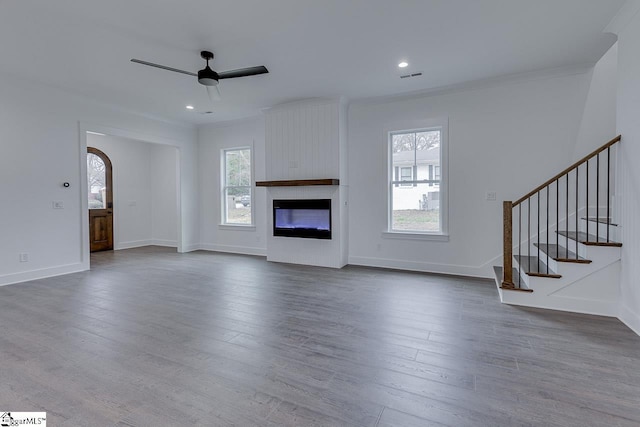 unfurnished living room with arched walkways, dark wood-style floors, visible vents, and ceiling fan