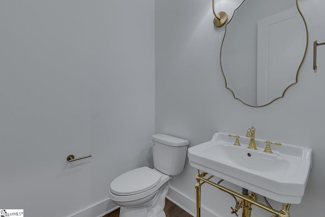 bathroom featuring baseboards, a sink, toilet, and wood finished floors