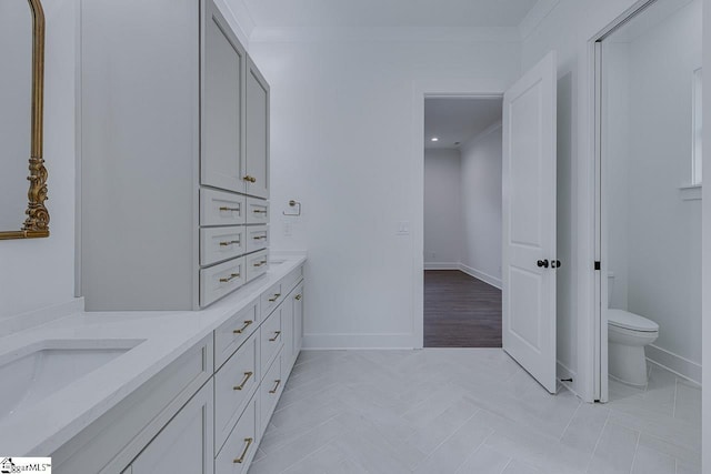 full bath with double vanity, baseboards, ornamental molding, and toilet