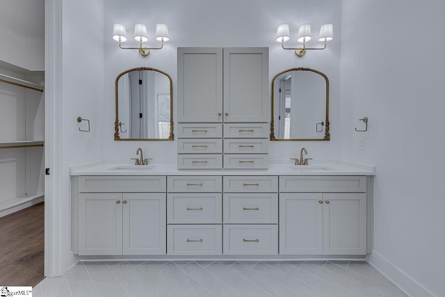bathroom with a sink, baseboards, and double vanity