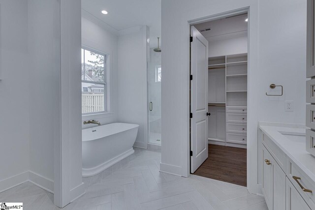 full bath with vanity, a stall shower, a walk in closet, visible vents, and a freestanding bath