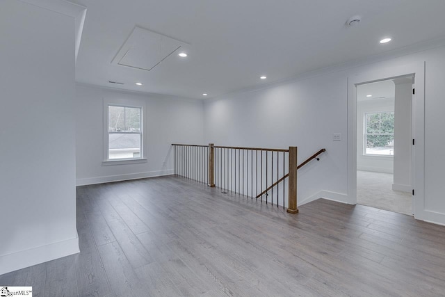 spare room featuring wood finished floors, attic access, ornamental molding, and plenty of natural light
