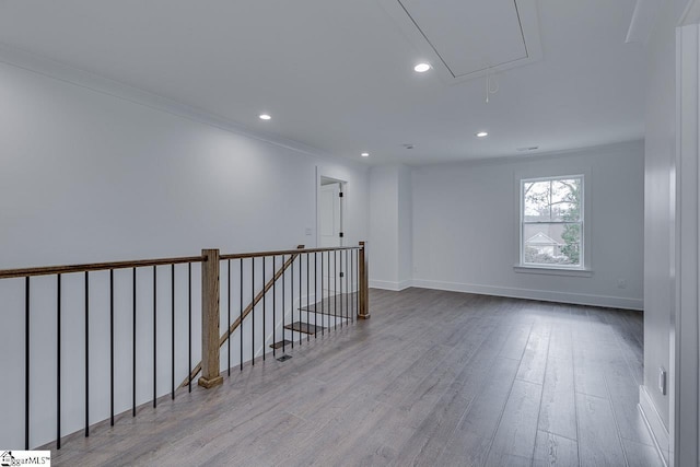 spare room featuring baseboards, ornamental molding, recessed lighting, attic access, and wood finished floors