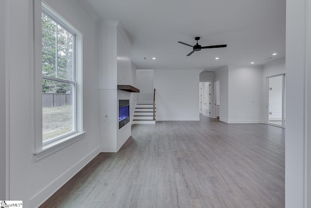 unfurnished living room featuring baseboards, a ceiling fan, a fireplace, recessed lighting, and wood finished floors