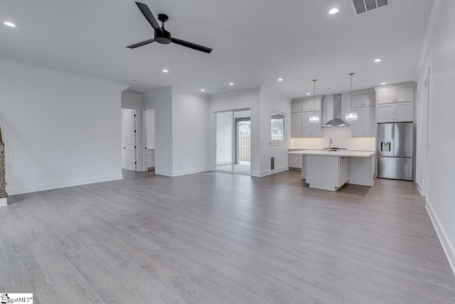 unfurnished living room with visible vents, a sink, light wood-style flooring, and ceiling fan