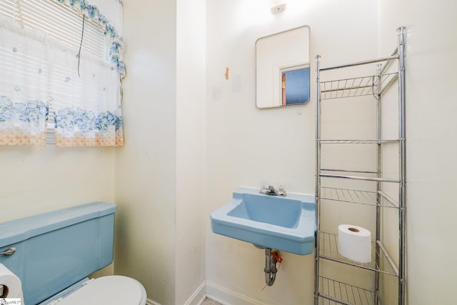 bathroom featuring a sink, toilet, and baseboards