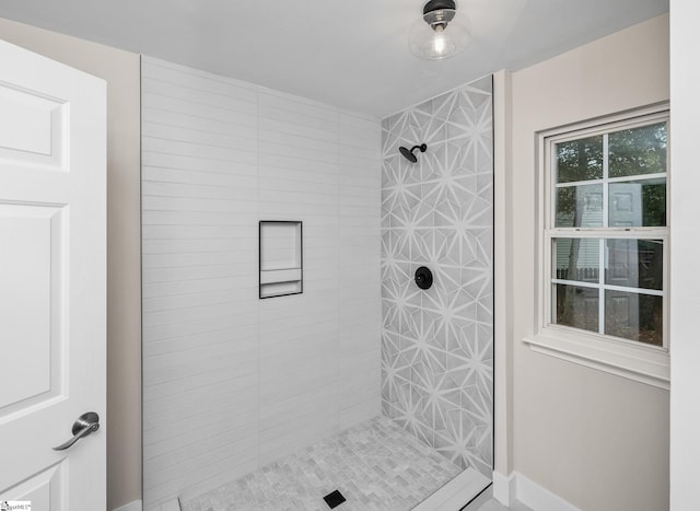 bathroom with baseboards and a tile shower