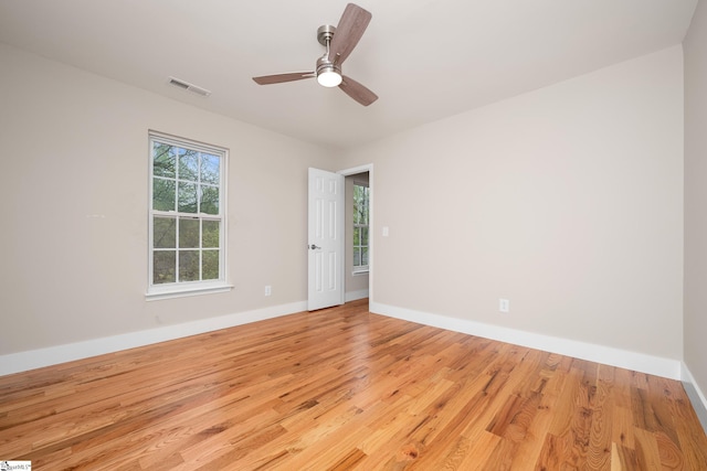 unfurnished room featuring light wood finished floors, baseboards, a ceiling fan, and visible vents