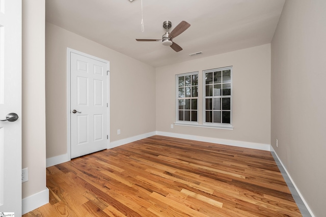 spare room featuring baseboards, light wood finished floors, ceiling fan, and visible vents