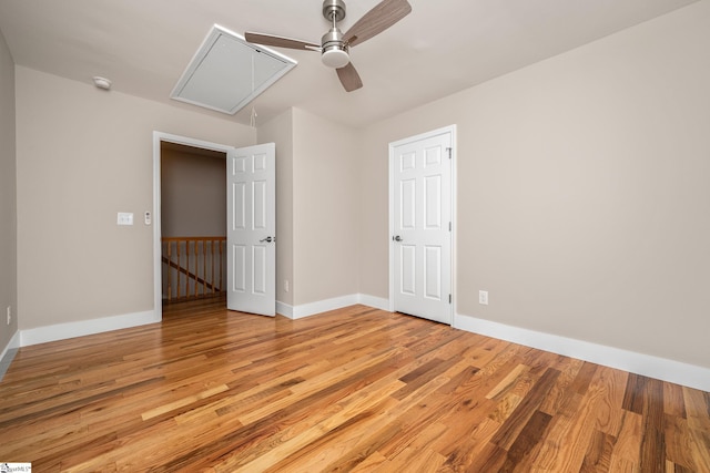 unfurnished room featuring baseboards, light wood-type flooring, attic access, and ceiling fan