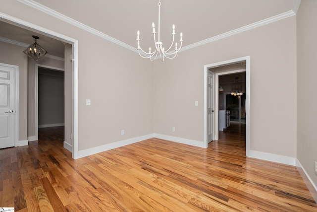 spare room featuring ornamental molding, light wood-style flooring, a chandelier, and baseboards